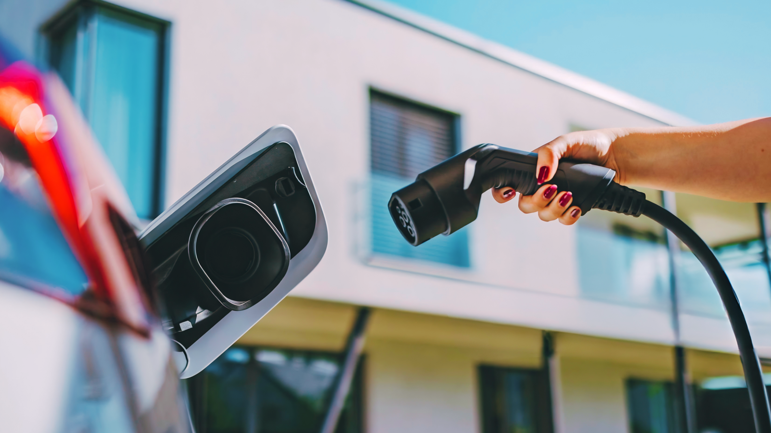 Mão conectando cabo Tipo 2 no veículo para mostrar a praticidade de escolher o melhor carregador carro elétrico residencial.